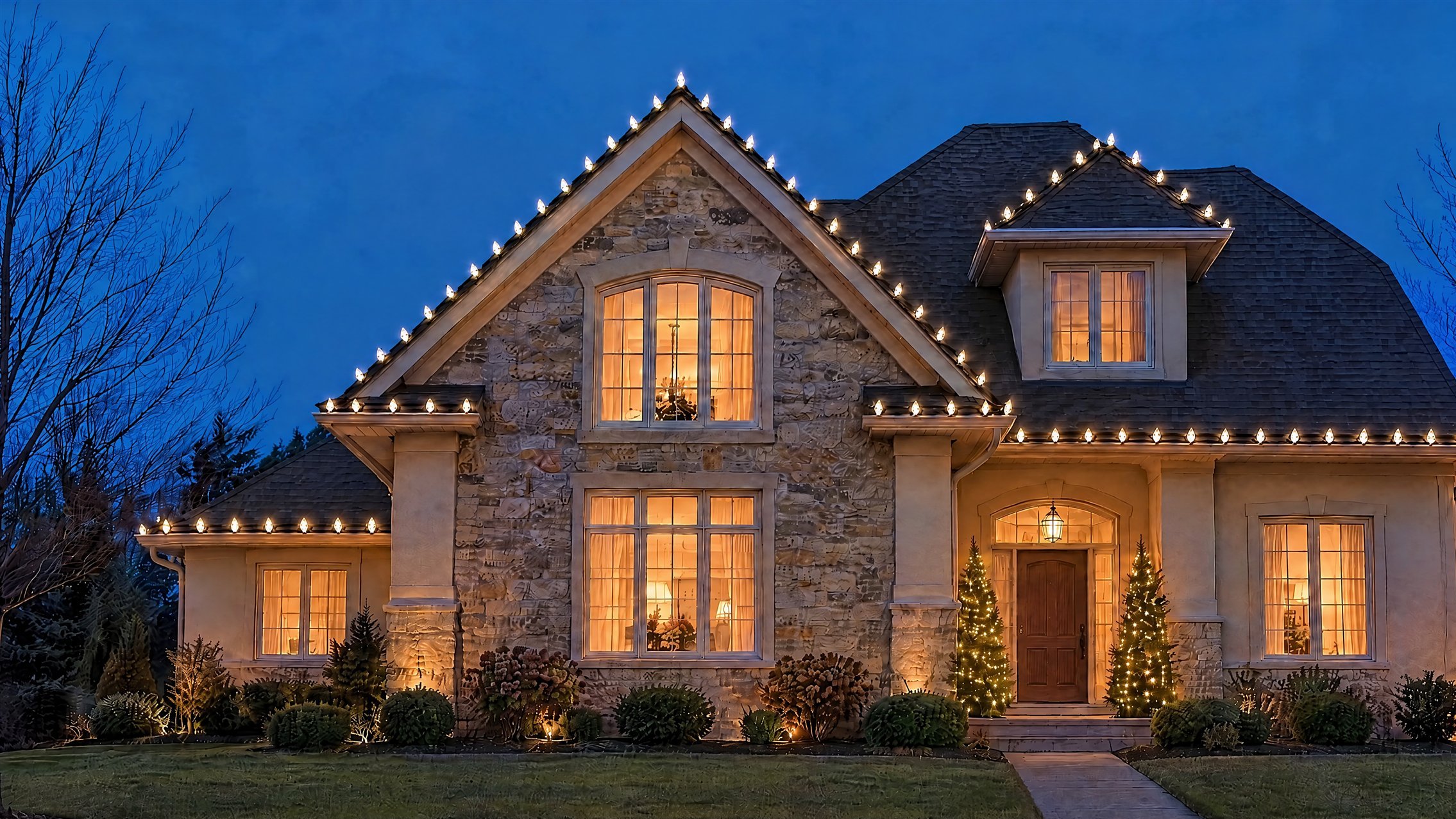 Maison avec ampoules blanc chaud sur les lignes de toit, colonnes et cèdres illuminés